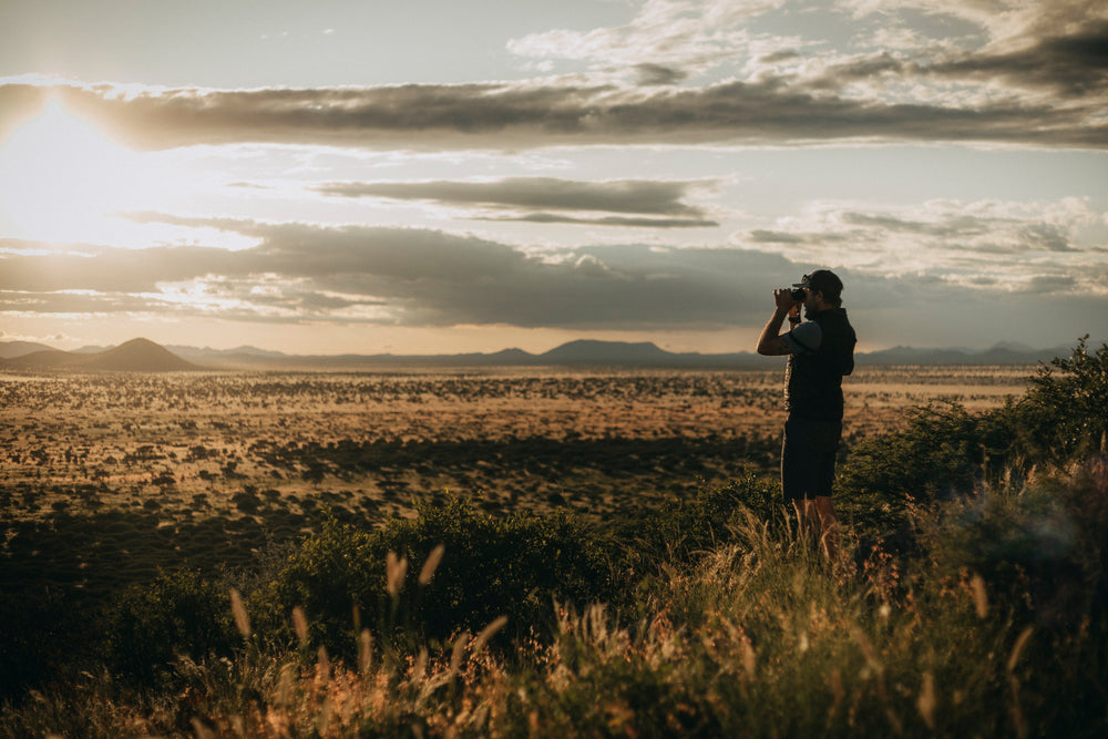 Person taking a photograph of a vast landscape with mountains in the background