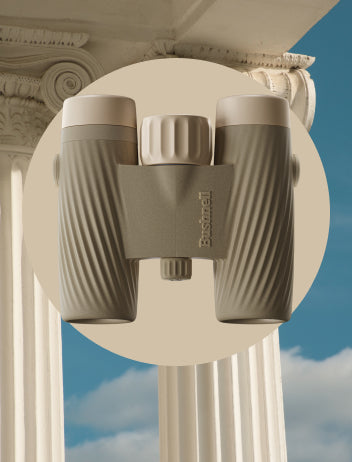 Binoculars with a brand logo held against classical architecture with a blue sky background