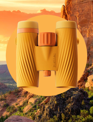 Yellow binoculars with orange accents against a scenic desert background