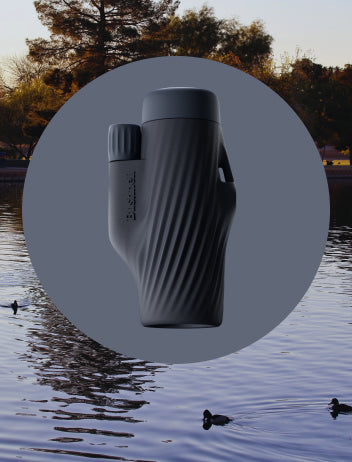 Black binoculars on a circular overlay with a blurred natural background