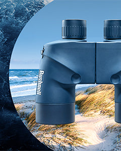 Blue Bushnell marine binoculars with a scenic background of ocean and beach