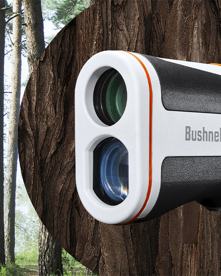 Bushnell white and black Rangefinder attached to a tree with a forest background