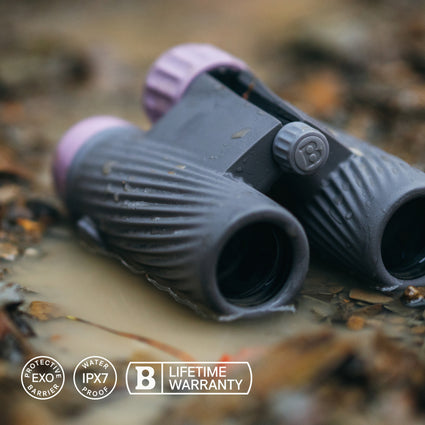 Binoculars on a natural surface with brand logos displayed.