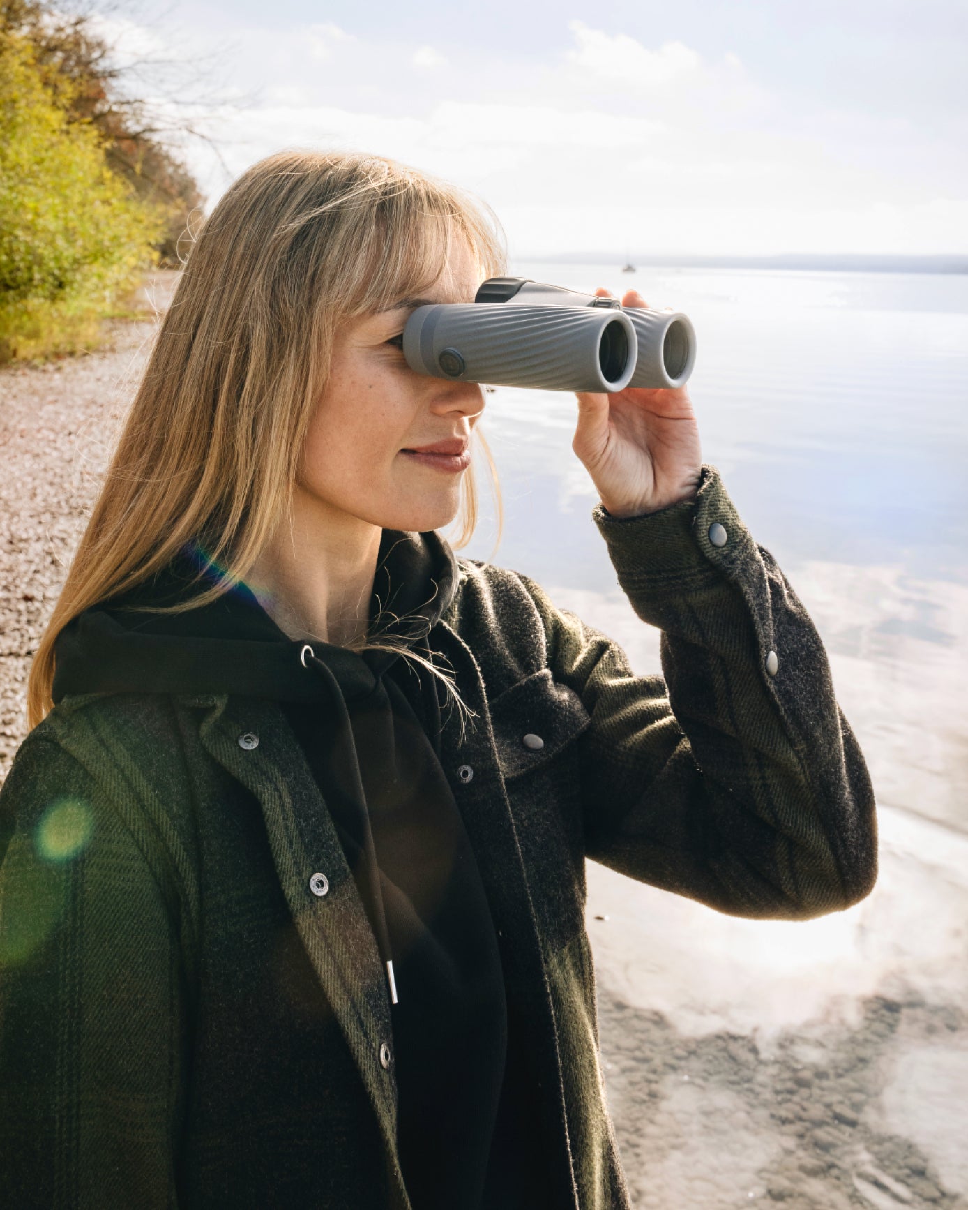 Woman using binoculars by a body of water