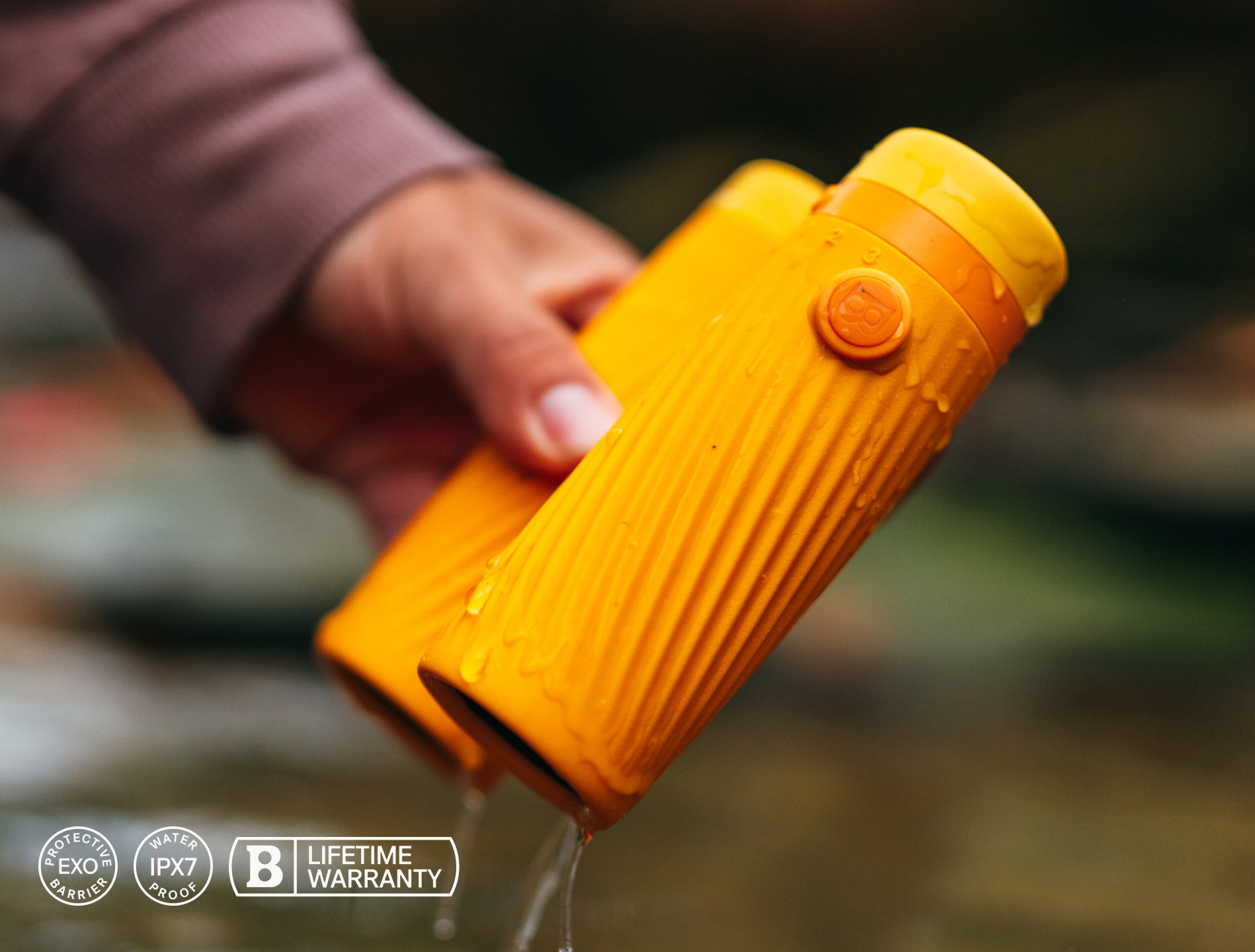 Person holding a yellow water bottle with a blurred natural background