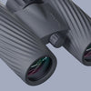 Close-up of a pair of Bushnell A3 binoculars with a brand logo on a light gray background