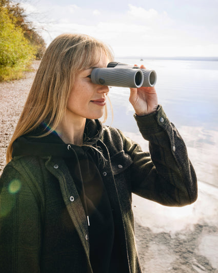 Woman using binoculars by a body of water