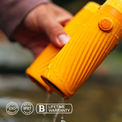 Hand holding a yellow water bottle with water dripping, featuring EXO, IPX7, and B brand logos.