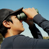 Person using Bushnell A5 binoculars in  color against a clear blue sky