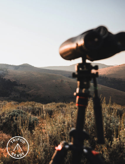 Telescope on a tripod with a scenic mountain landscape in the background