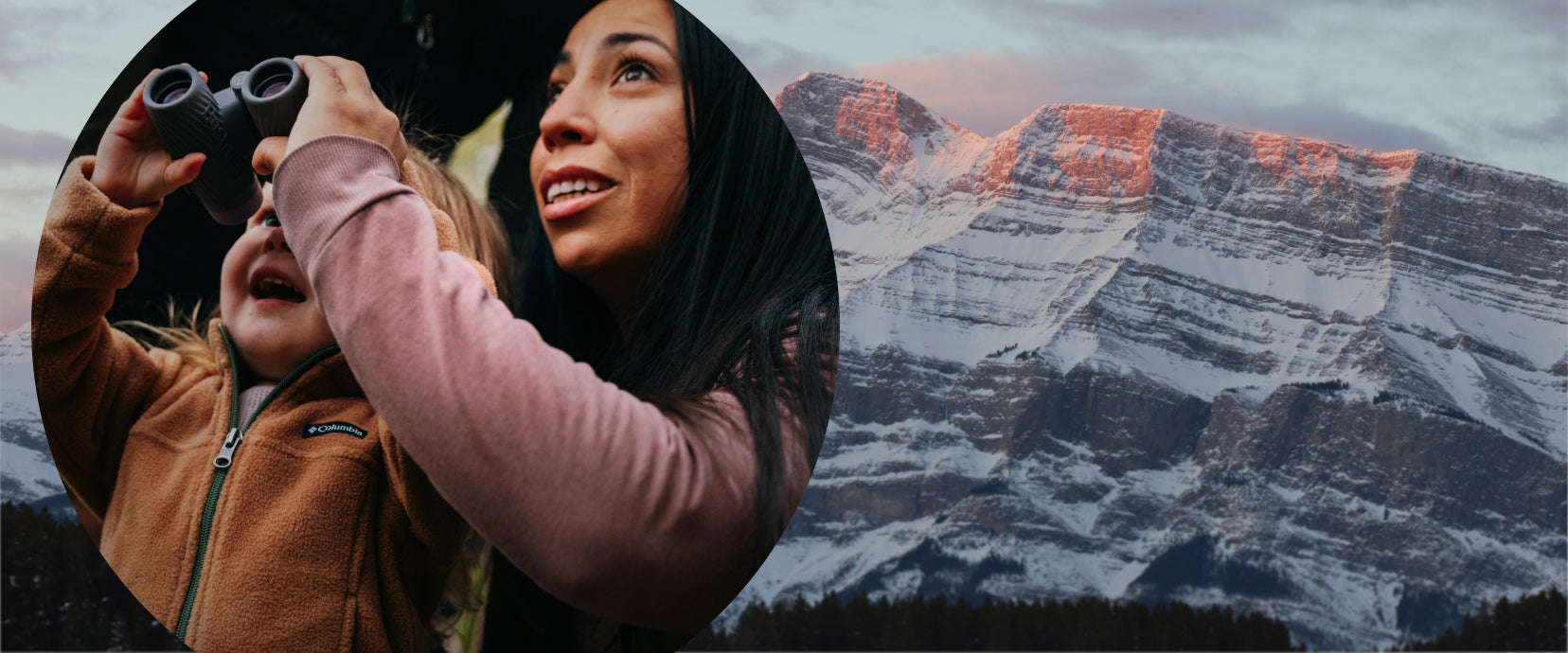 Two people with binoculars against a mountainous landscape
