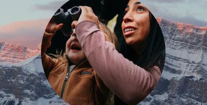 Woman and child looking through binoculars with mountainous landscape in the background