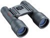 Front right view of black roof prism binoculars with red Tasco logo and 10x32 in white on the right lens, set on a transparent background
