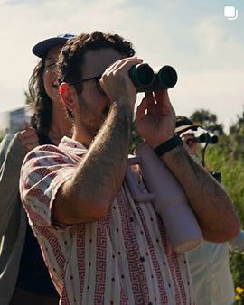 Person using binoculars with a scenic background