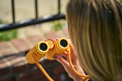 Person holding yellow binoculars with a blurred background